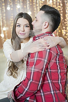 Young future parents on the background of bright lights of garlands.