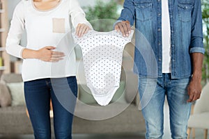 young future parents with chlidrens clothes at home