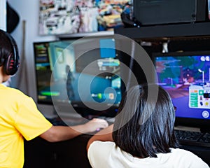 A young gamer girl at home in a room with brother playing with friends on the networks in computer video games