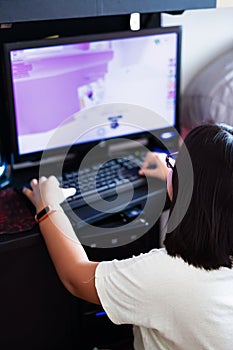 A young gamer girl at home in a room playing with friends on the networks in computer video games