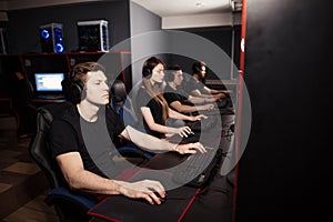 Young gamers playing video game while spending weekend at pc gaming club