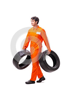 The young garage worker with tyre isolated on white