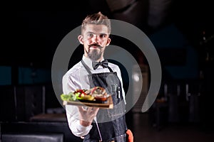 Young garcon serves dish at a festive event.