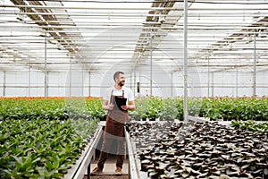 Young gardener working with plants in greenhouse