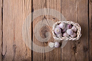 Young garlic in a basket of wicker vine lies on an old wooden rustic table. top view