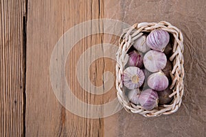 Young garlic in a basket of wicker vine lies on an old wooden rustic table. Top View. Close-up