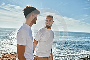 Young gay couple smiling happy walking at the beach promenade