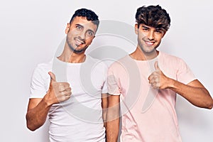 Young gay couple wearing casual clothes doing happy thumbs up gesture with hand