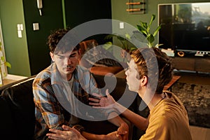 Young gay couple wearing casual clothing arguing and gesturing in living room at home