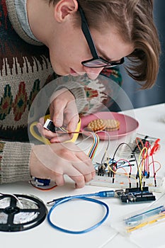 Young geek connecting wires to breadboard