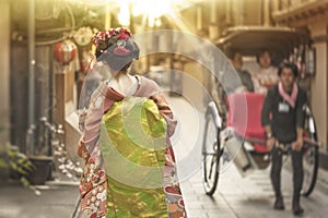 Young geisha walking in an alley of Kyoto in the sunset light. photo