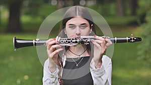 A young Georgian girl holds a clarinet in front of her face.