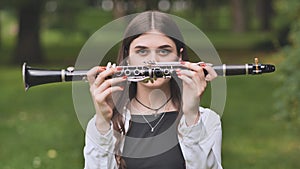 A young Georgian girl holds a clarinet in front of her face.