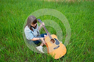Young girl with acoustic guitar model person posing photography on green grass meadow summer Jule day time