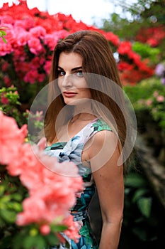 Young girl admires blooming azaleas in a botanical garden. Closeup of butiful girl