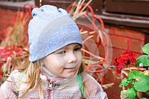 Young girl admiring a vibrant red flower in a beautiful garden setting