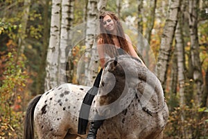 Young girl with appaloosa horse in autumn