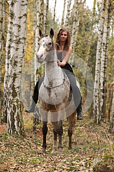 Young girl with appaloosa horse in autumn