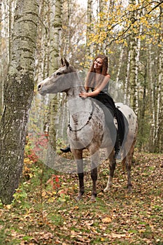 Young girl with appaloosa horse in autumn
