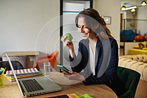 Young girl with an apple and smartphone at table