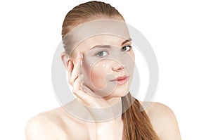 Young girl applying moisturizer cream on her face.