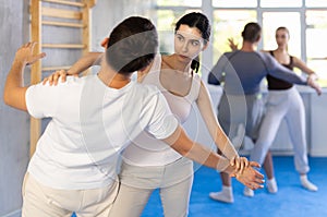 Young girl applying throwing technique on her opponent in sports hall