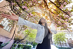 Young girl with arms wide open and enjoing the cherry tree street