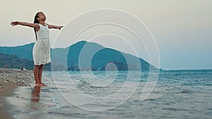 Young girl with arms wide open on sea beach. Beautiful girl spreading arms