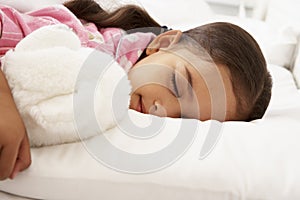 Young Girl Asleep In Bed With Cuddly Toy photo