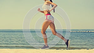 Young girl athlete, in shorts and top running on the beach in summer, morning exercise.