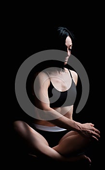 Young girl of athletic appearance with black hair sits in a lotus position