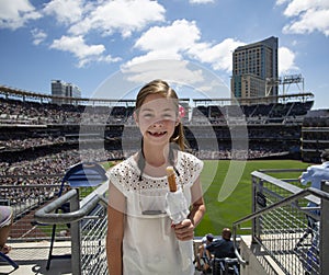 Young Girl attending her first professional baseball game. Smiling, happy and holding a churro photo
