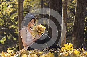 Young girl in autumn forest with a bouquet of mapple leaves