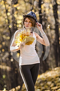 Young girl in autumn forest with a bouquet of mapple leaves