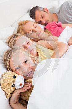 Young girl awake next to her sleeping family