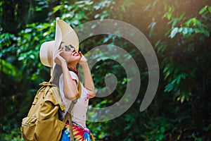 Young girl with backpack enjoying  travel nature in the forest Lush green trees. Happy smiling woman With nature travel, rural