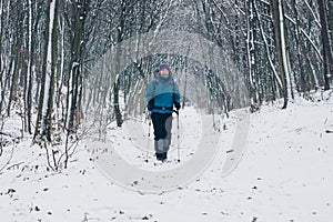 Young girl with backpack hikes on the path through the winter forest