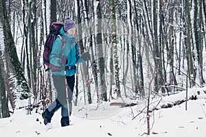 Young girl with backpack hikes through the winter forest