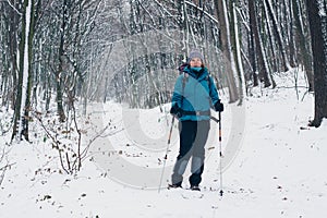 Young girl with backpack hikes through the winter forest