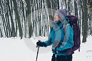 Young girl with backpack looks above standing alone the winter forest