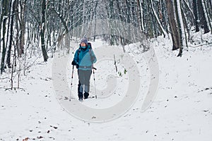 Young girl with backpack looks aside while hiking through the winter forest