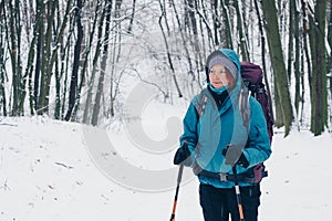 Young girl with backpack looks aside standing alone the winter forest