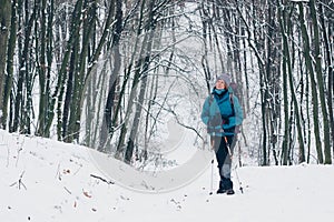 Young girl with backpack looks aside standing the winter forest