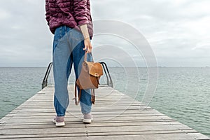 Young girl with a backpack, looks at the sea, on a wooden pier. Close-up. Freedom. Trips
