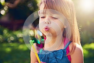 Young girl, backyard and blowing pinwheel, garden and enjoying freedom of outside and fun. Pretty little child, outdoor