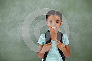 Young girl with bagpack against chalk board photo