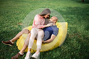 Young girl and balding man relaxing on air hammock in the garden. Spring or summer love story