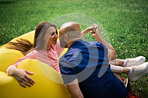 Young girl and balding man relaxing on air hammock in the garden. Spring or summer love story