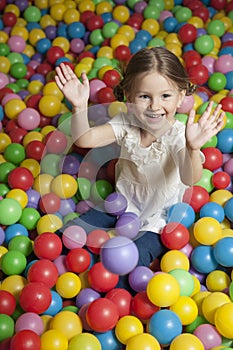 Young girl in ball pit throwing colored balls