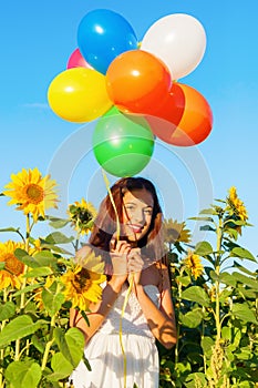 Young girl with balloons in a sunflower field